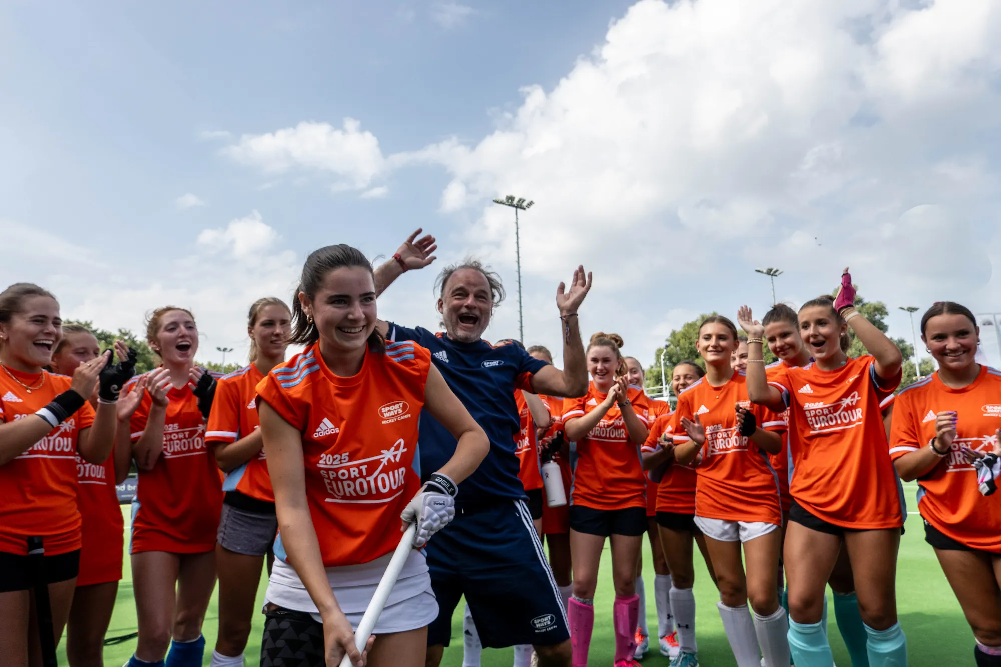 A Sport EuroTour athlete with her stick and glove, her coach cheering behind her, at the Amsterdam training club